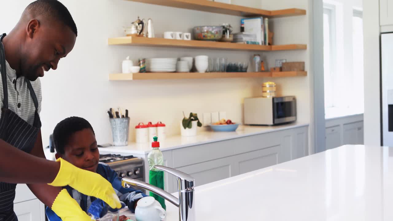 Father and son cleaning utensils in kitchen