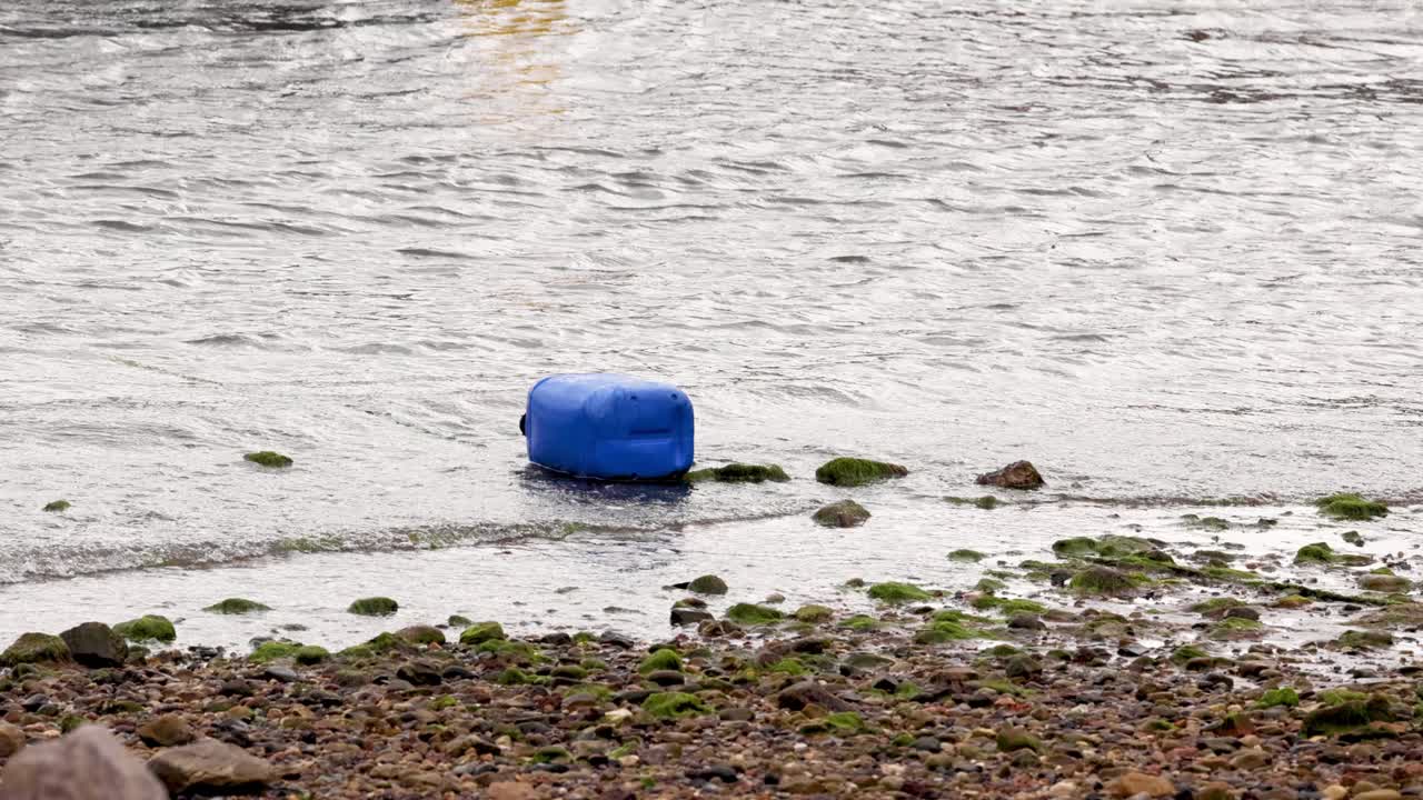 голубая бочка движется с волнами на скалистом пляже