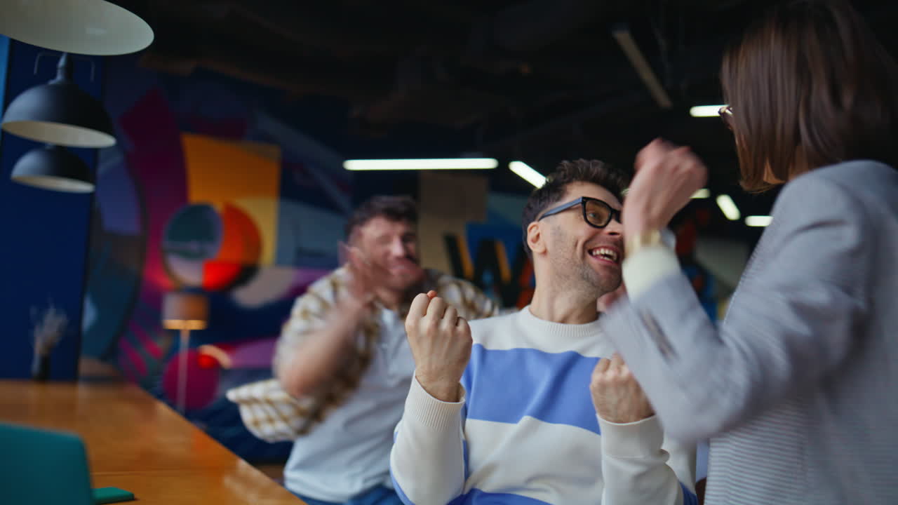 Three coworkers rejoicing successful deal in modern office closeup. Startup team