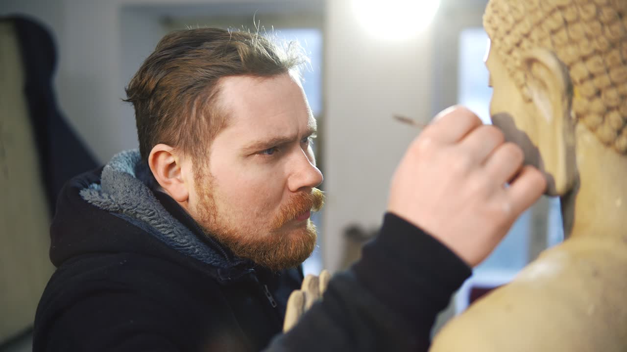 retrato de un artista que trabaja en la cara de la estatua de buda usando una herramienta especial en un taller