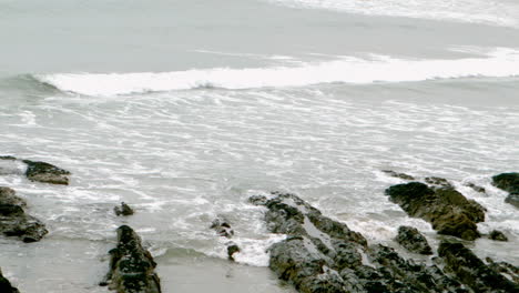 waves rolling in on the beach over rocks