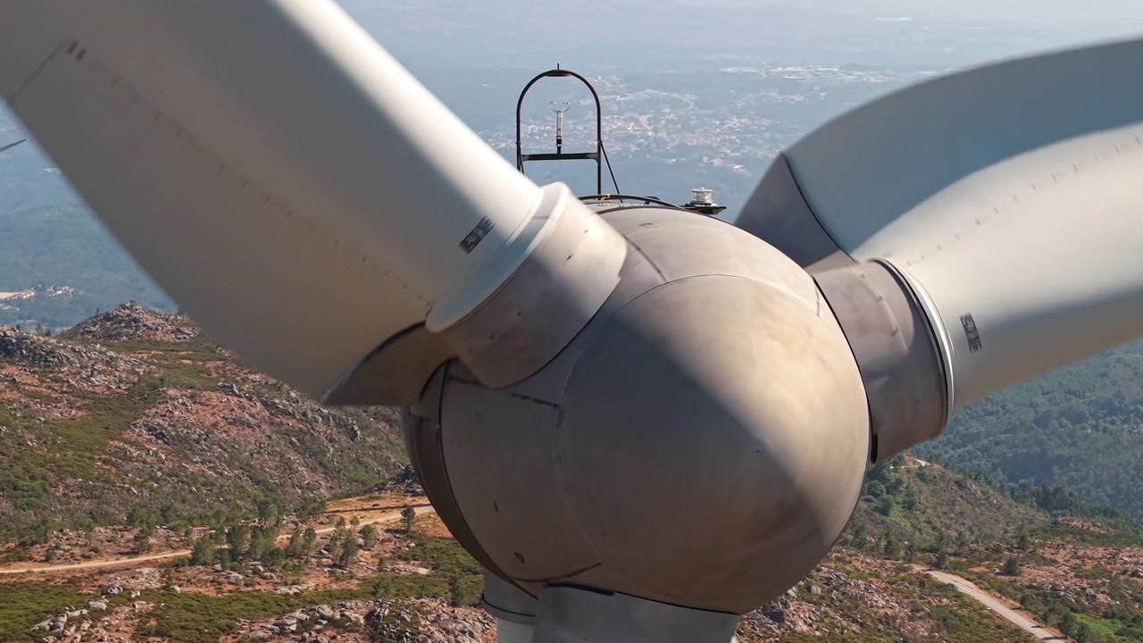 Nær turbinrotor med en annen vindturbin på steinete åsrygg