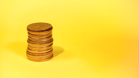 la mano apilando diferentes monedas en un fondo colorido