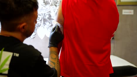 rear shot of a tattoo artist removing the tracing of a dog tattoo on the arm of his client