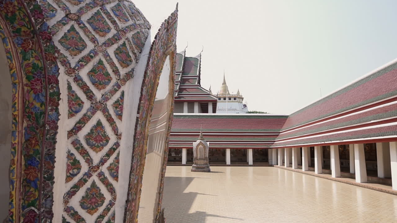 Slow Motion slide right to reveal the golden mountain buddhist temple in the city of Bangkok in Thailand from the grounds of another empty temple