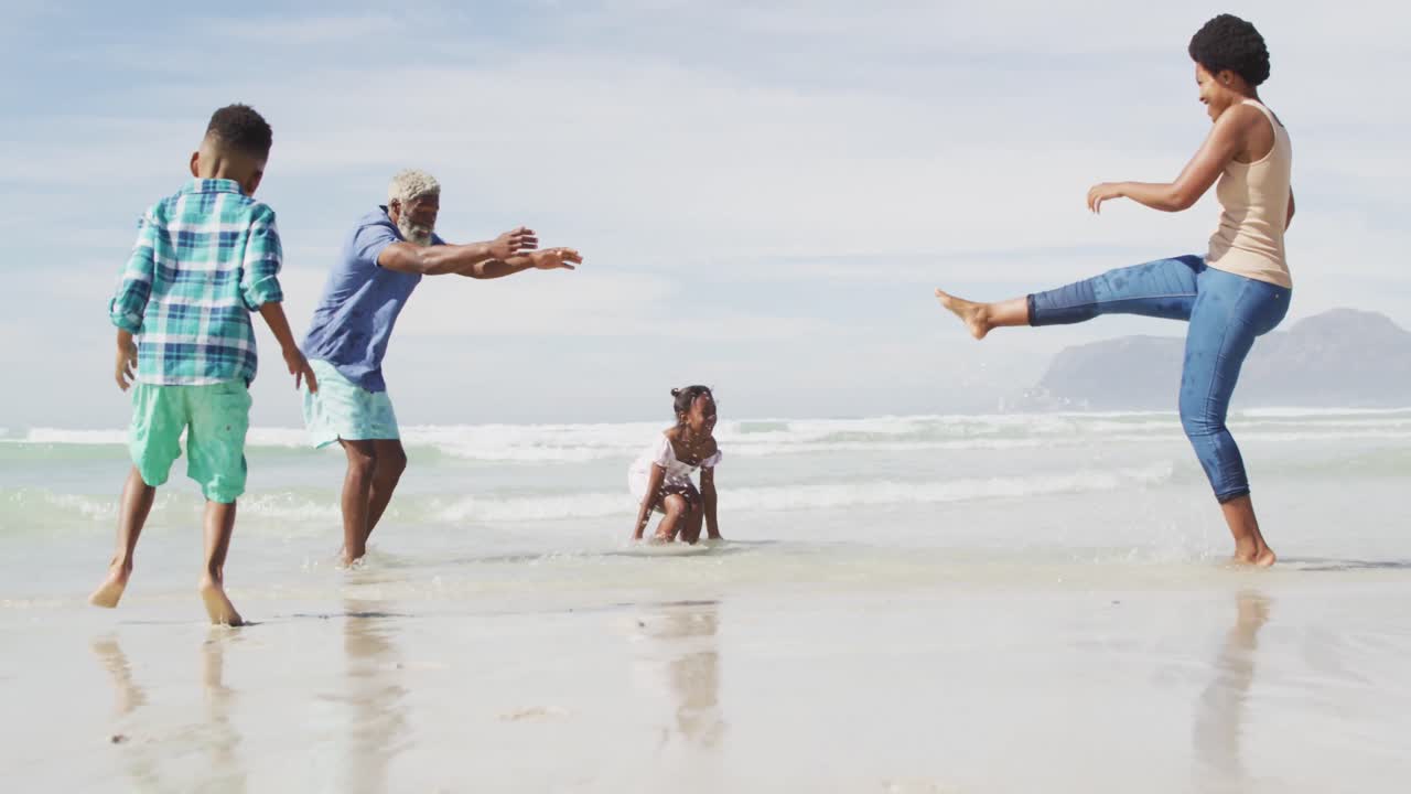Felice coppia afroamericana che gioca con i bambini su una spiaggia soleggiata