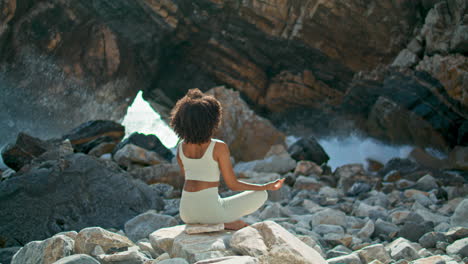 back view girl sitting lotus pose in front cliff of ursa beach. woman meditating