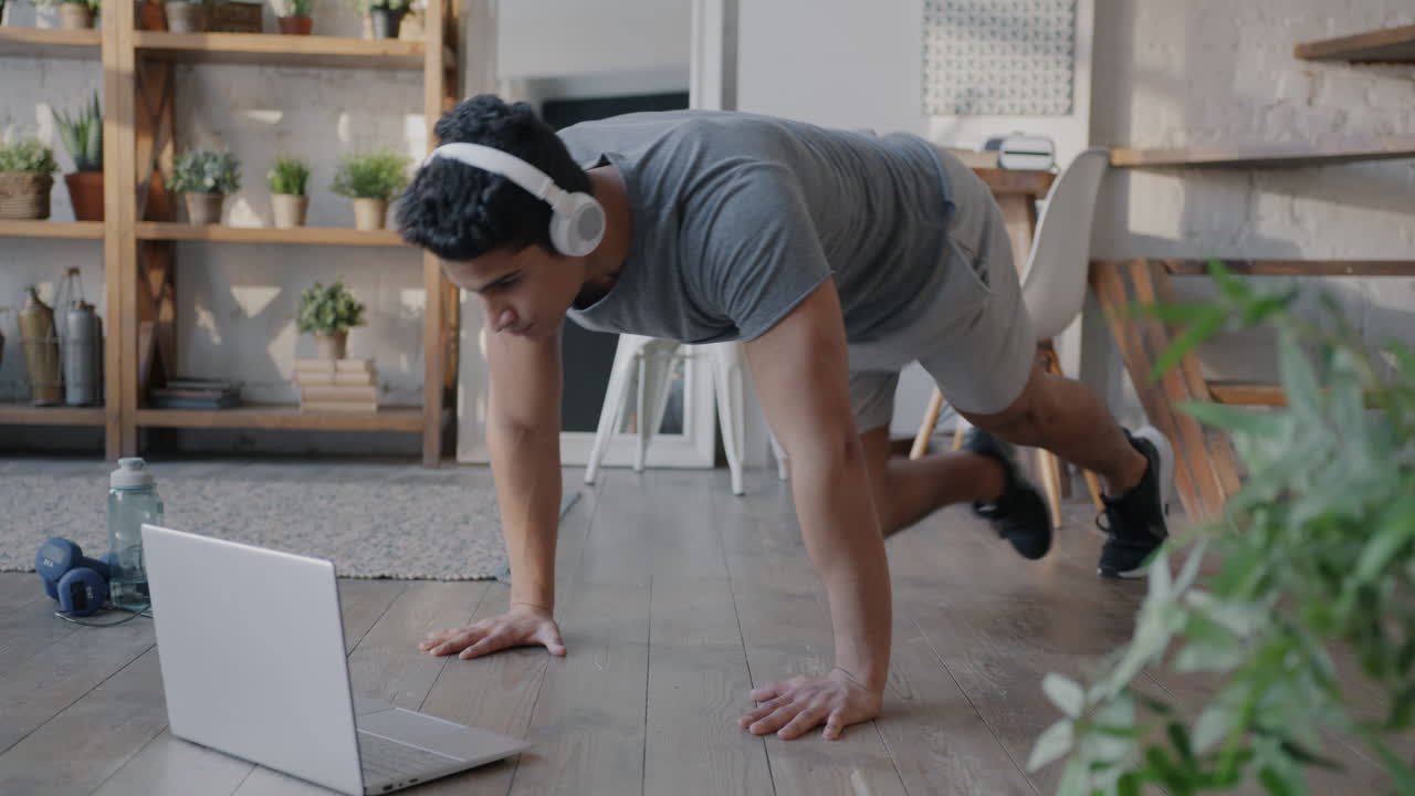 hombre haciendo ejercicios de fitness en línea en casa