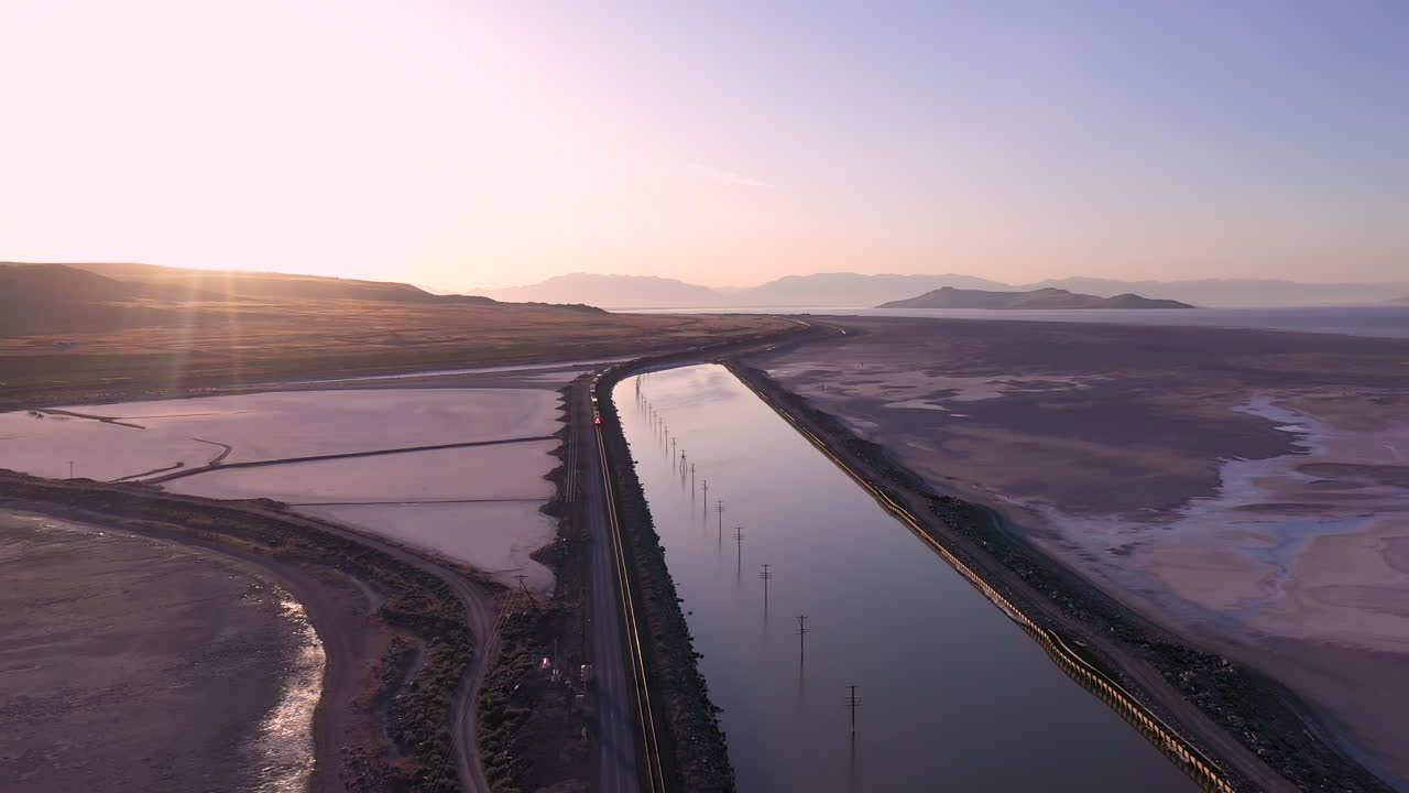 toma cinematográfica de drones al amanecer del lago salado rosa en utah y el tren que se aproxima