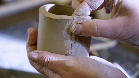 hands shaping raw clay for a ceramic vessel