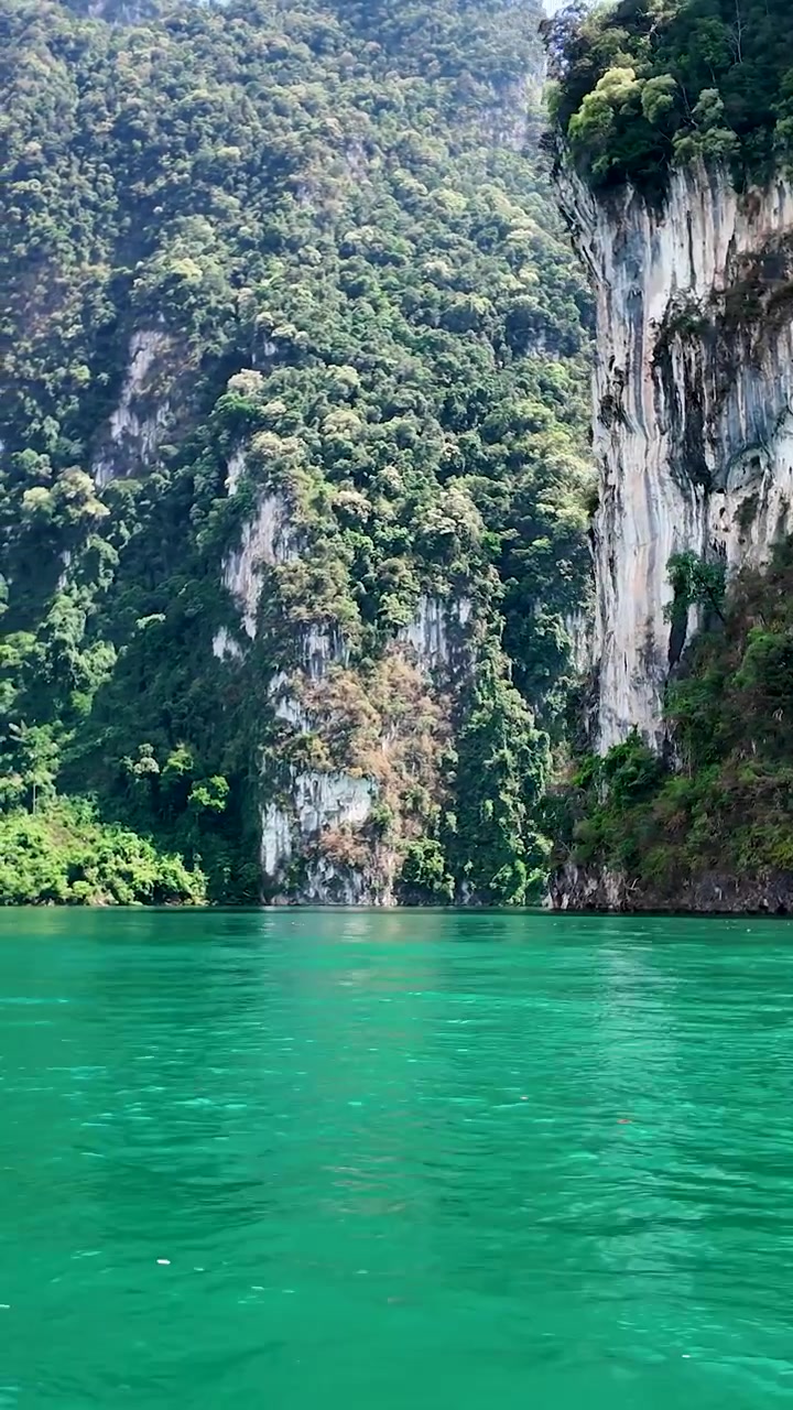 Giro in barca panoramico attraverso un lago color smeraldo circondato da imponenti scogliere calcaree e giungla tropicale nel Parco Nazionale di Khao Sok, Thailandia