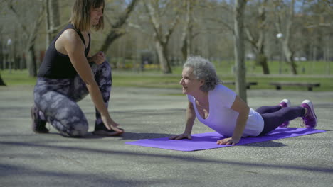 sporty elderly woman practicing yoga with trainer.