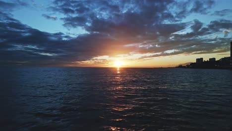 vista aérea del sol bajo las nubes sobre el mar, moviéndose hacia atrás
