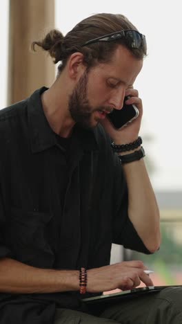 Man talking on phone and using tablet