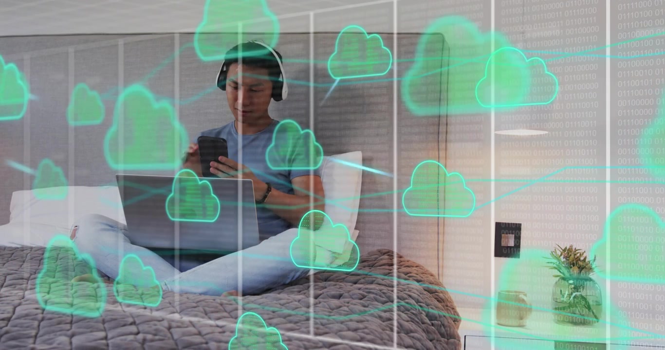 Man reaching for headphones, typing on laptop showing multiplying cloud computing icons around him