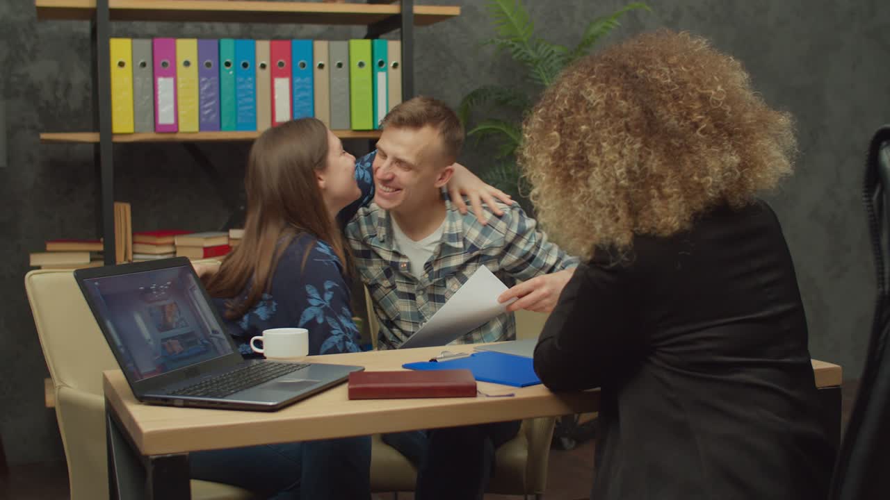 una pareja de casados emocionados celebrando la compra exitosa de una casa nueva en la oficina.