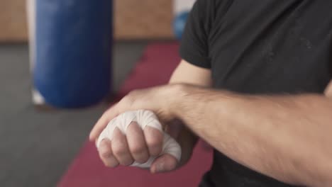 close-up of a young athletic man wrapping his hand with white box bandage