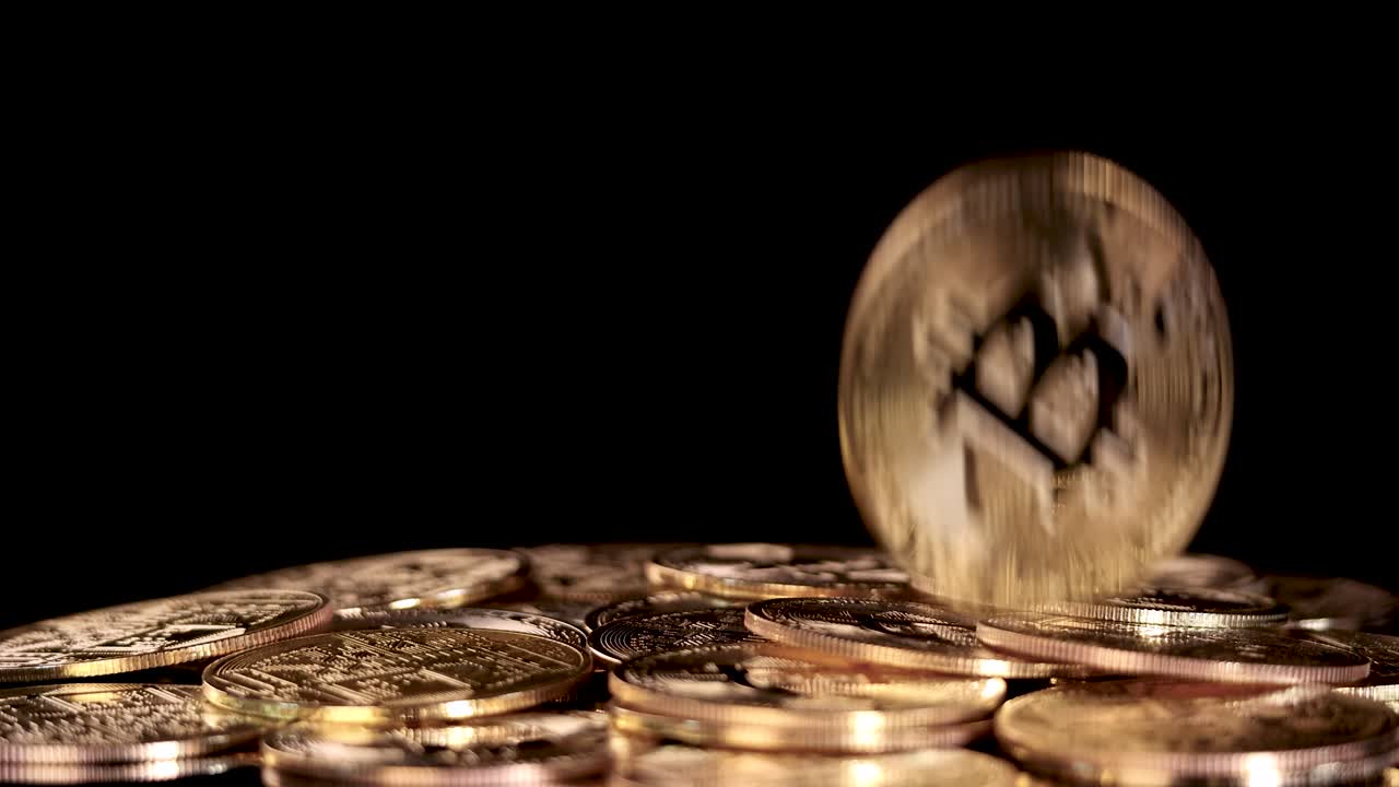 A golden digital currency token drops onto a pile of coins, dramatic lighting, black background