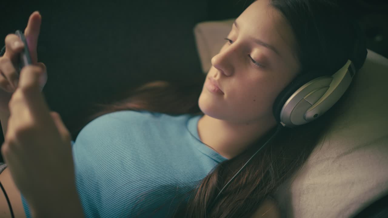 Adolescente relaxando em casa, ouvindo música com fones de ouvido e usando seu smartphone. Um momento calmo e íntimo de lazer digital em um ambiente aconchegante