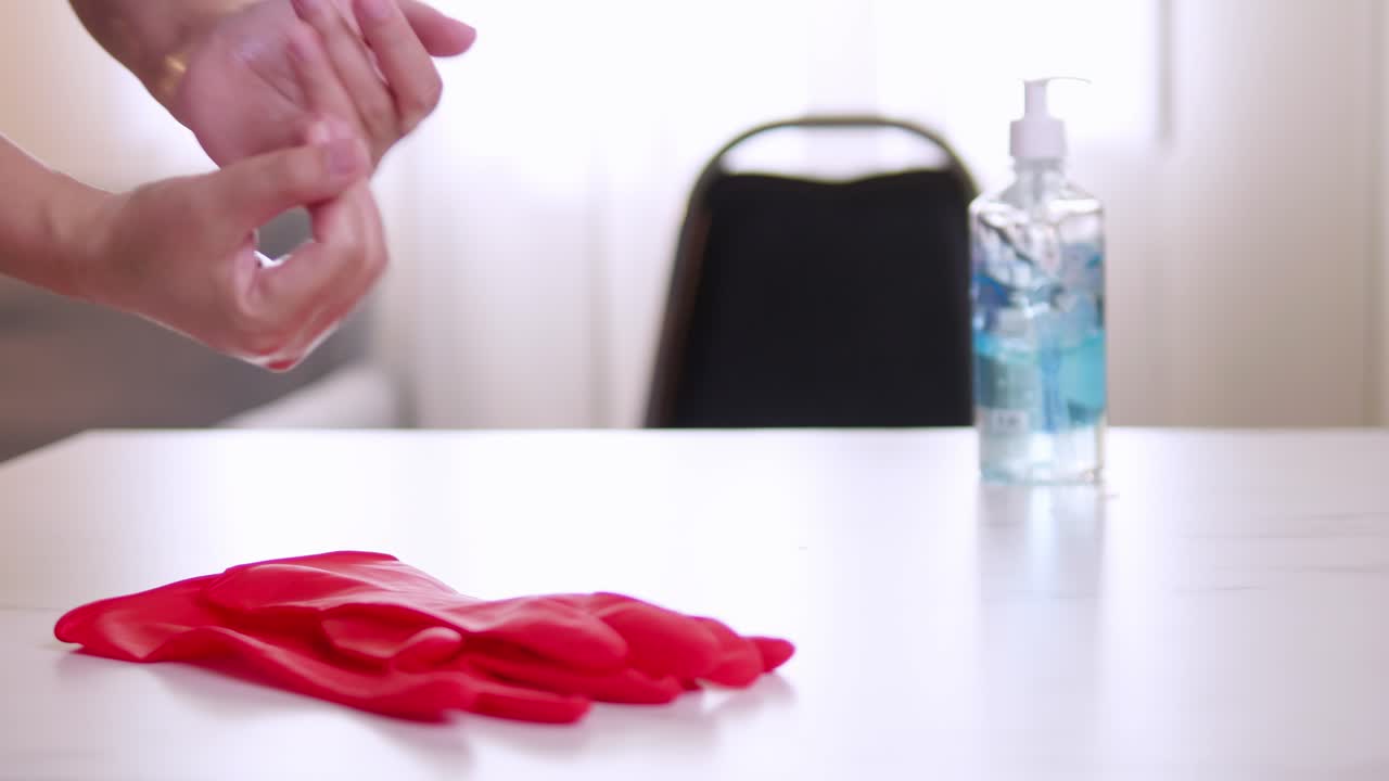 Gel desinfectante de manos para coronavirus para la higiene y prevención de la propagación de COVID-19, después de quitarse el guante rojo dejado sobre la mesa