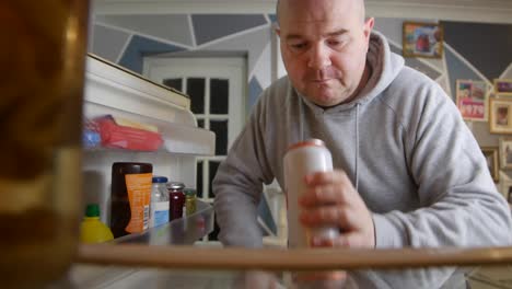 el hombre abre el refrigerador buscando una bebida
