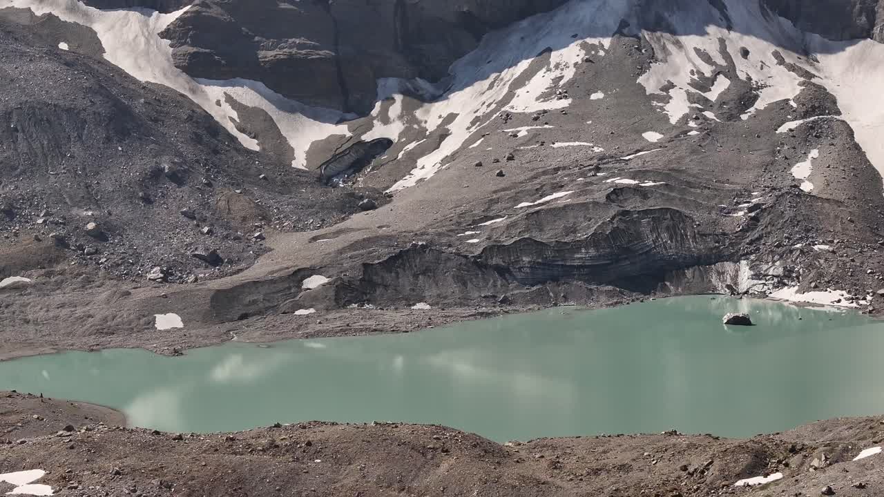 Glacial lake near Urnerboden in Klausenpass surrounded by rocky alpine slopes in Uri, Switzerland