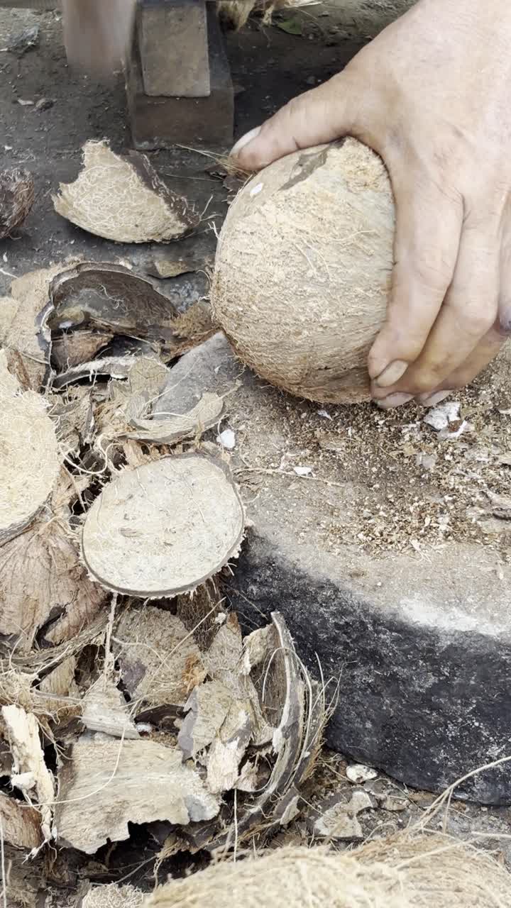 Detailní záběr rukou loupajících kokos mačetou