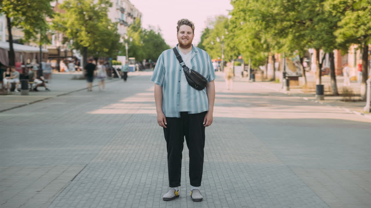 Uomo con camicia a righe e pantaloni neri in una strada cittadina
