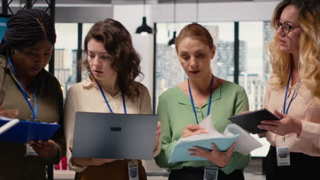 vertical video businesswomen gather around documents and laptops as a unified team
