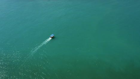 Dolly-in-aerial-drone-shot-following-a-small-transport-boat-sailing-on-a-tropical-turquoise-river-from-the-Restinga-beach-to-the-Barra-do-Cunhaú-beach-in-Rio-Grande-do-Norte,-Brazil-on-a-summer-day