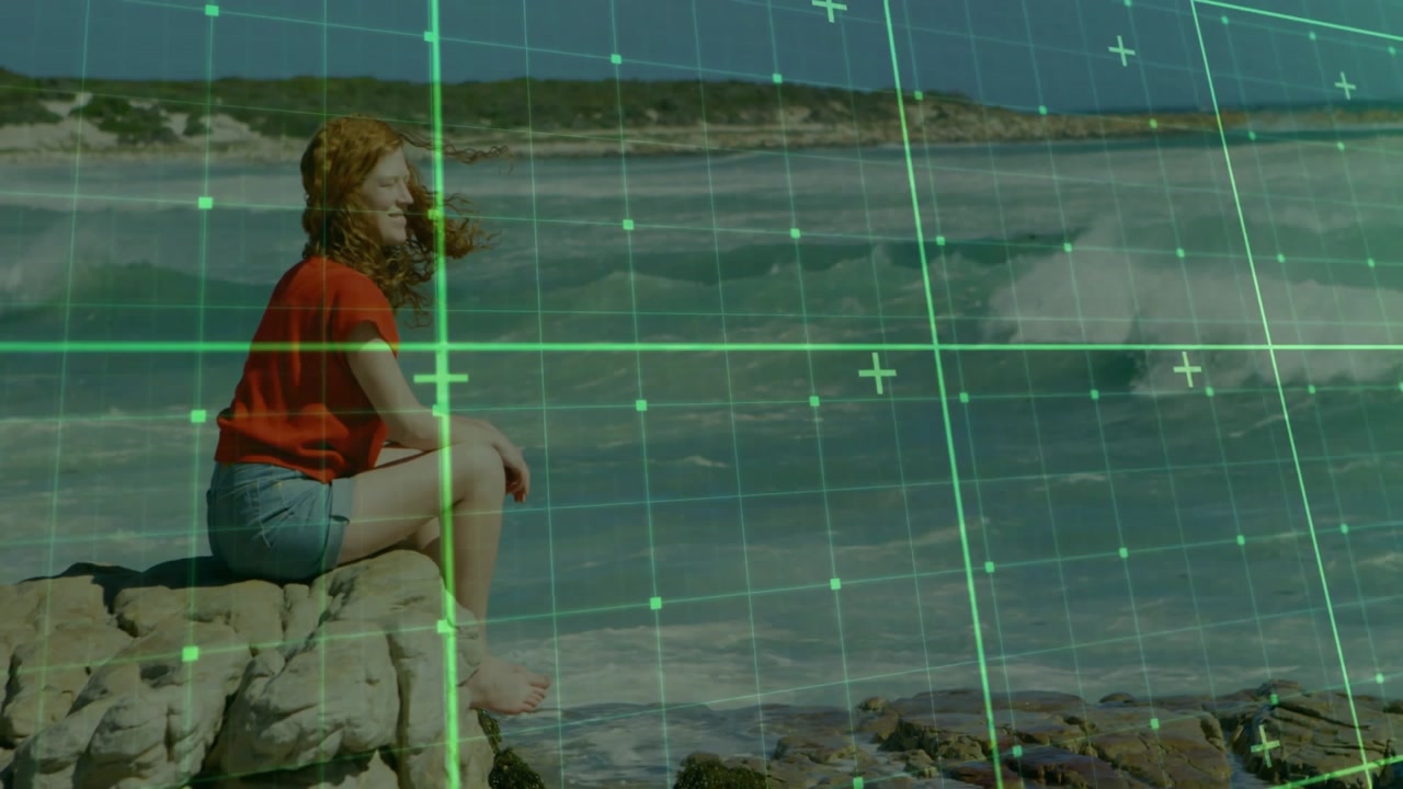 woman sitting on rock facing sea, starting green grid scanning shore for tech mapping
