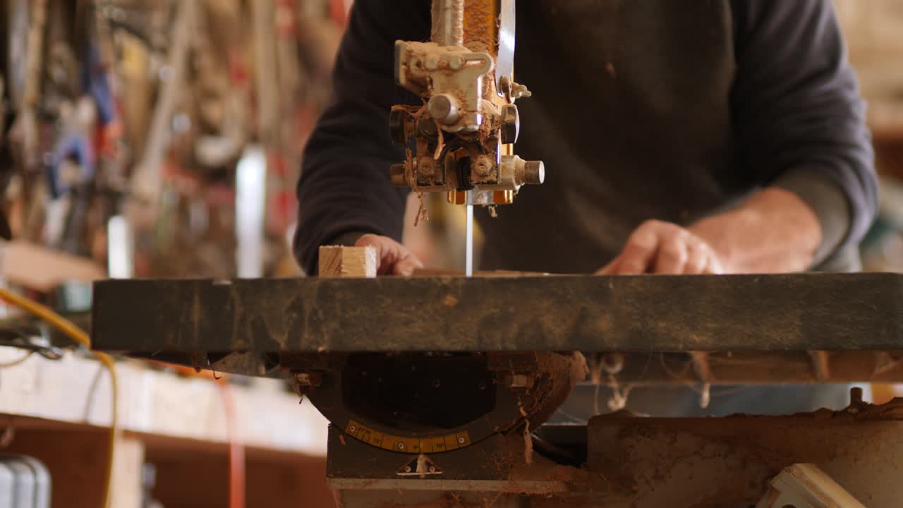 Carpenter cutting wood with bandsaw in workshop