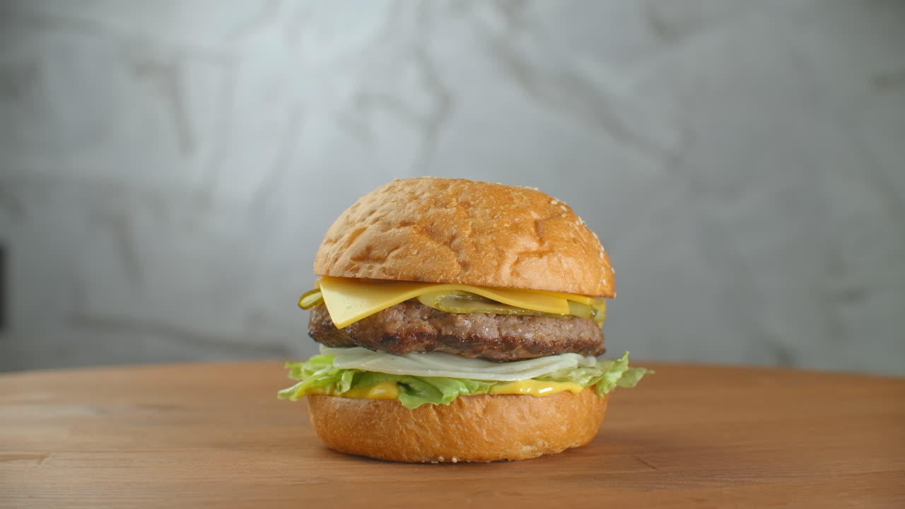 yummy concepto de comida rápida. hamburguesa fresca a la parrilla casera con carne patata tomates pepino lechuga cebolla y semillas de sésamo. estilo de vida no saludable. fondo de la comida.