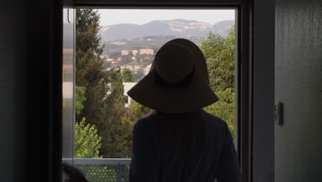 woman in a hat enjoying a drink on a balcony overlooking a beautiful view