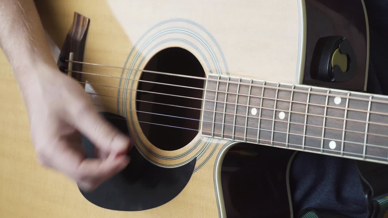 A close up of young man strumming an Acoustic Guitar.