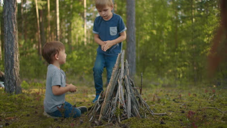 Zwei-Brüder-Im-Alter-Von-3-Bis-6-Jahren-Sammeln-Im-Wald-Während-Eines-Familiencampingausflugs-Bei-Sonnenuntergang-Lagerfeuerstäbe-Und-Stellen-Sie-Auf