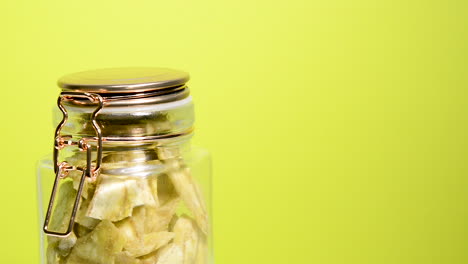 chips de plátano en un tarro de albañil hermético girando sobre un fondo amarillo neón