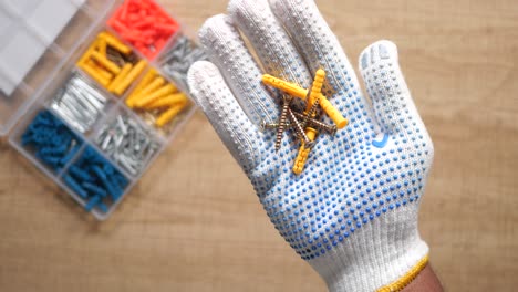 hand holding screws and wall anchors with a plastic storage box