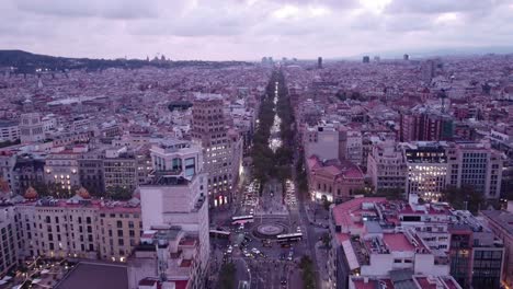 Barcelona-cityscape-with-streets-and-buildings-at-dusk,-lights-starting-to-glow,-aerial-view