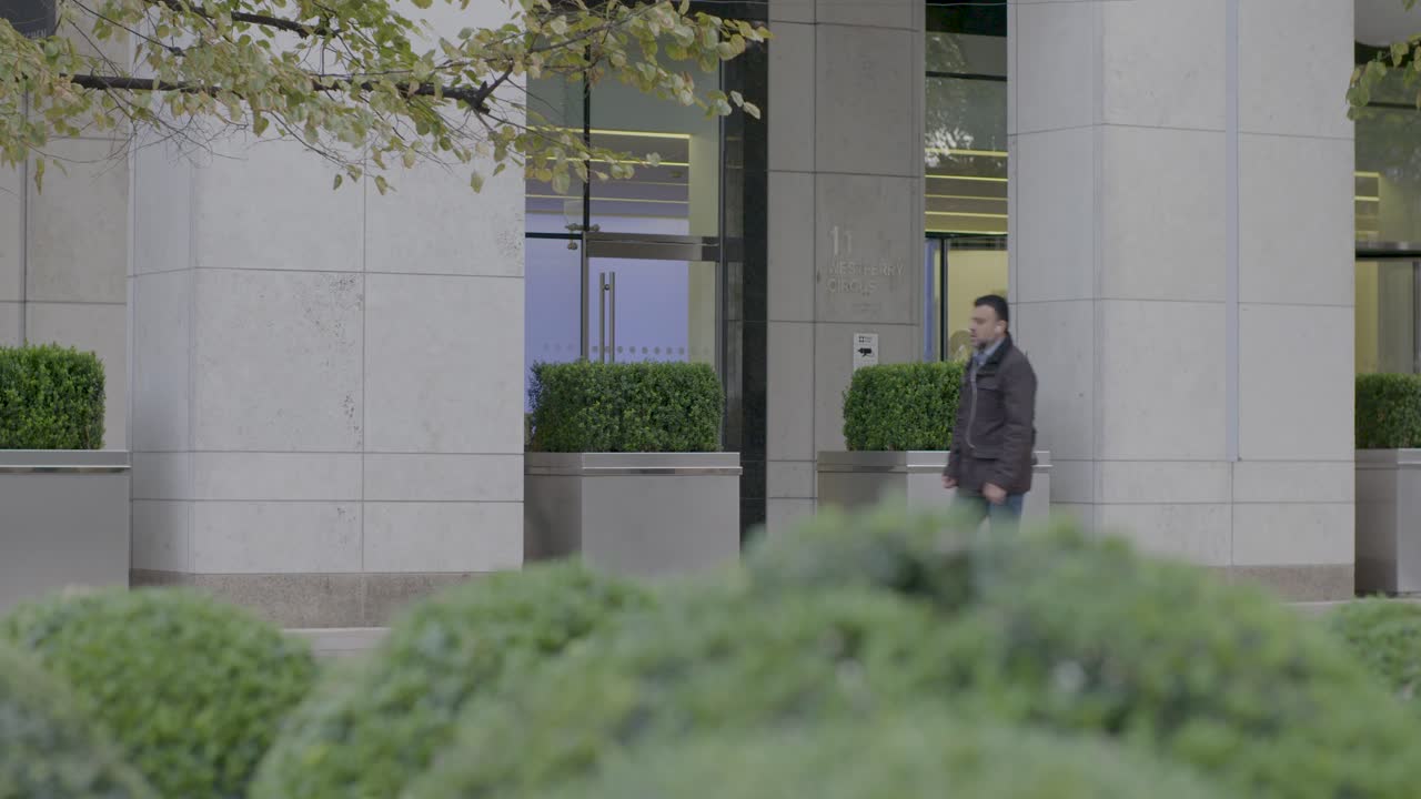 Man Walking Past Modern Office Building in London
