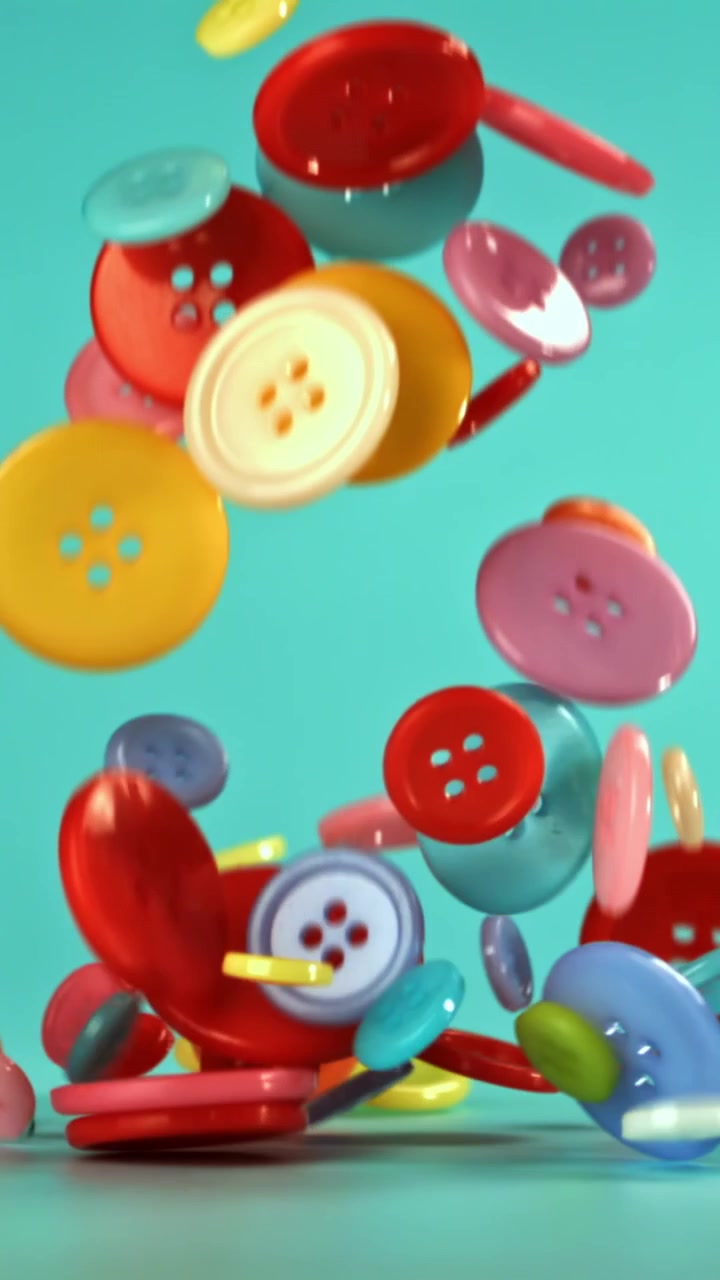 Assorted Colorful Buttons Falling in Slow Motion on Teal Background