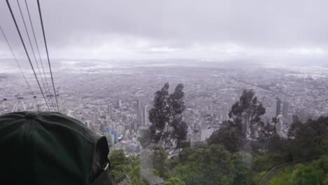 a view of bogotá, colombia through the window from a moving aerial tramway car in the monserrate hills