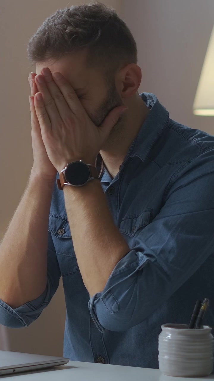 Giovane uomo esausto che si strofina gli occhi dopo aver lavorato al portatile