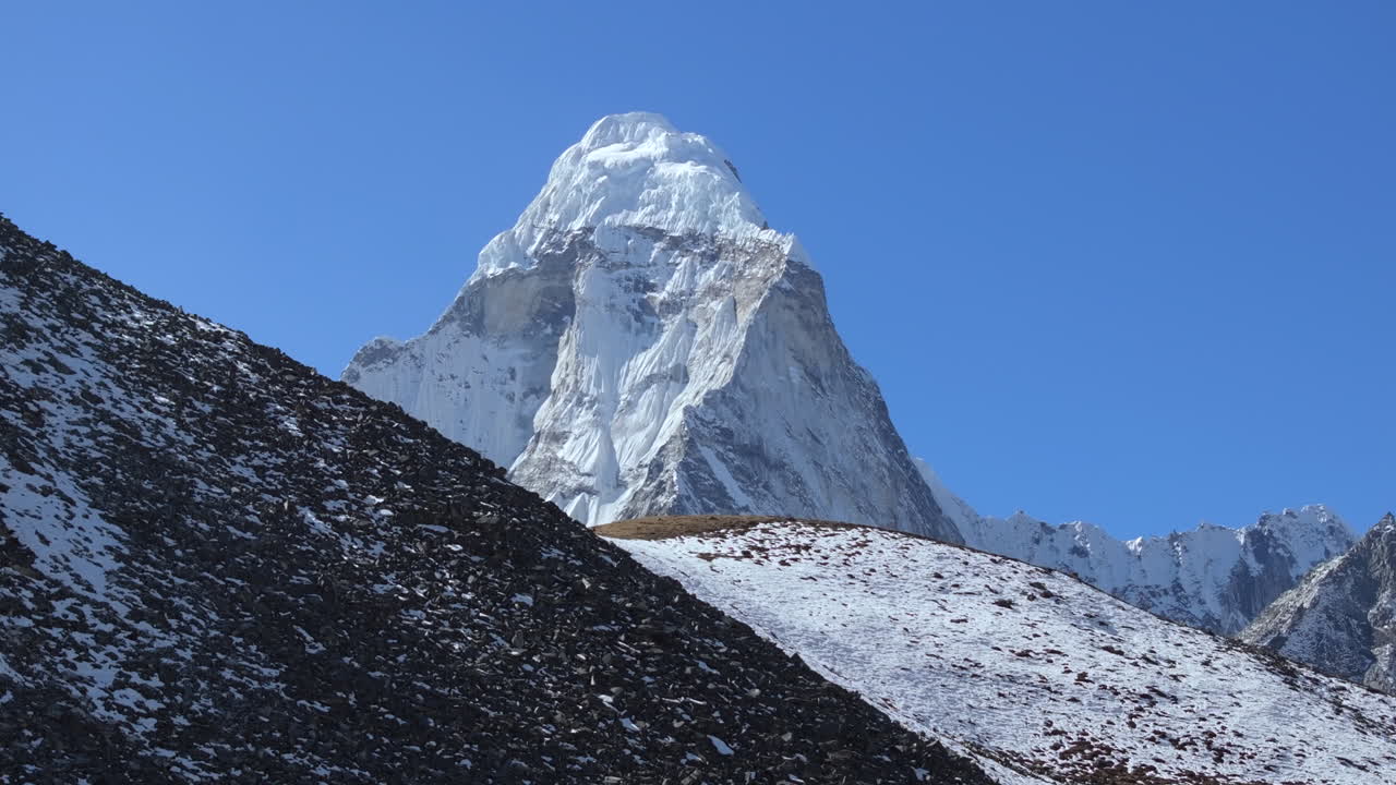 Rivelazione cinematografica del Monte Ama Dablam che si erge oltre il terreno montuoso roccioso nella regione dell'Everest in Nepal, mostrando il drammatico paesaggio alpino himalayano.