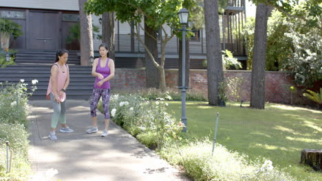 Amigas-Asiáticas-Enfocadas-Estirándose-En-El-Jardín-En-Un-Día-Soleado,-Cámara-Lenta