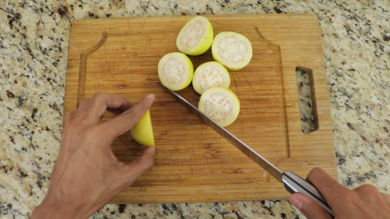 preparación de alimentos en pov, corte de frutos frescos de guayaba en la tabla de cortar
