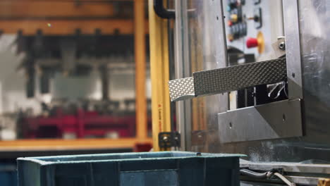 raw car parts dropping out of a machine in a bucket in the background a big hydraulic press working in the automated production line