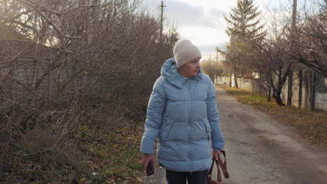 elderly woman walking down a country road in autumn