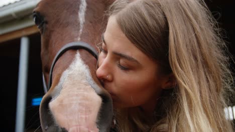 mujer besando a un caballo en el establo 4k