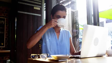 mujer de negocios usando una computadora portátil mientras toma café